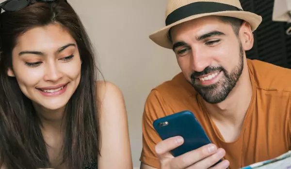 couple inside of a house checking something on a phone