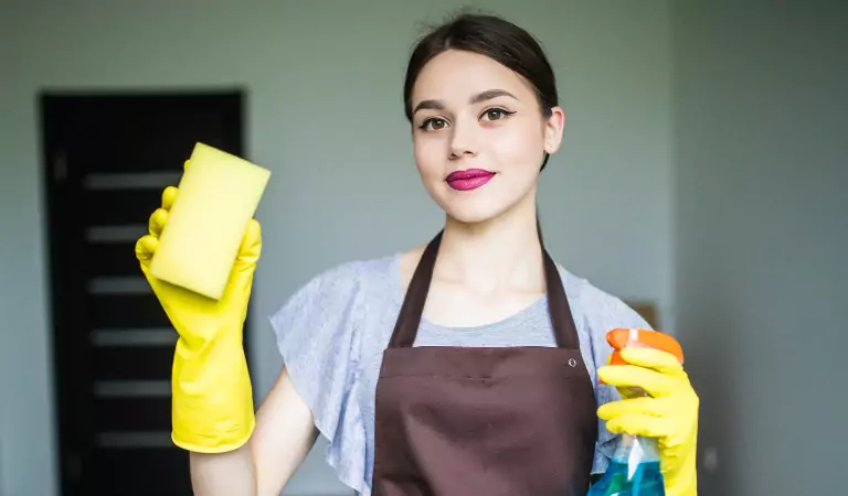 young woman holding a cleaning spray and a mop
