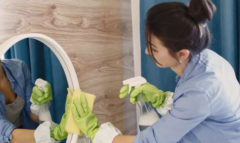 woman cleaning up a bathroom mirror
