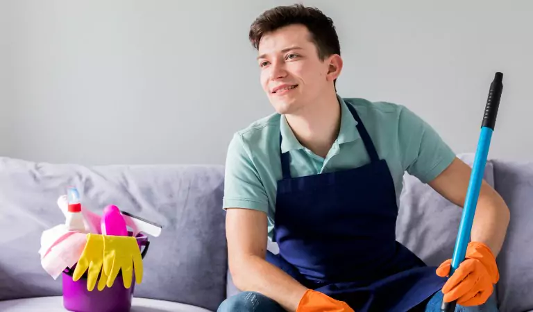 young man sitting on a couch with some cleaning supplies