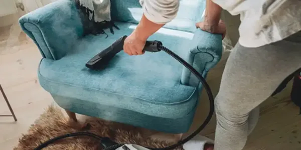 Lady performing steam cleaning on sofa