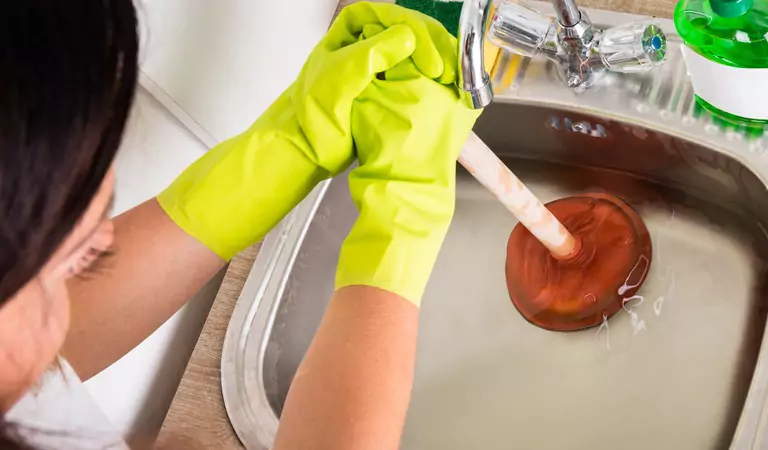 young woman trying to unblock the blocked sink