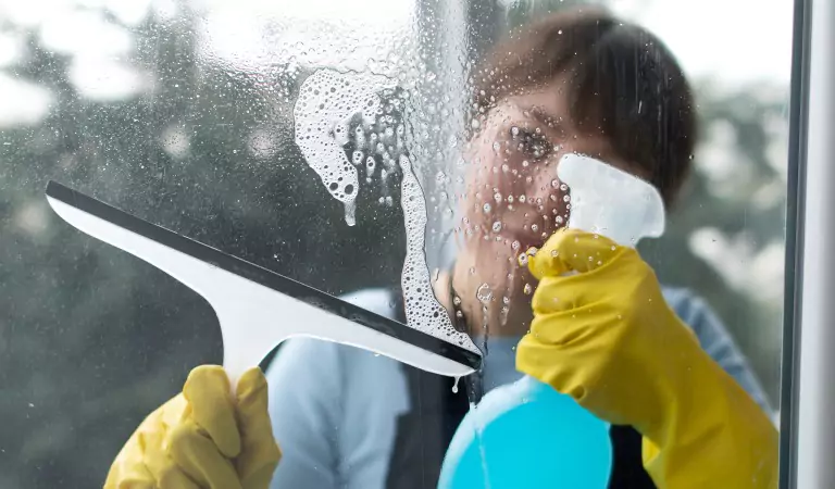 young woman holding a wiper in her hands cleaning a window