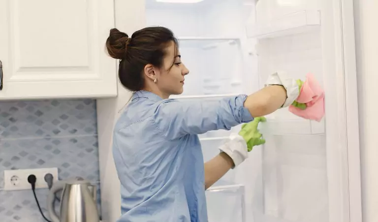 woman organising a fridge and cleaning it